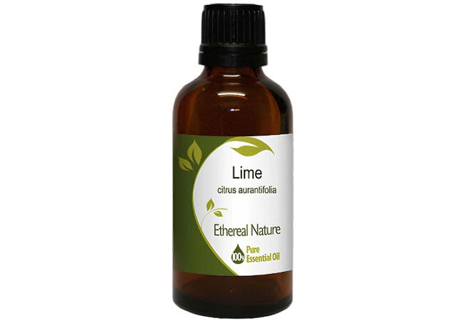 Pure lime essential oil in glass bottle next to fresh lime fruit